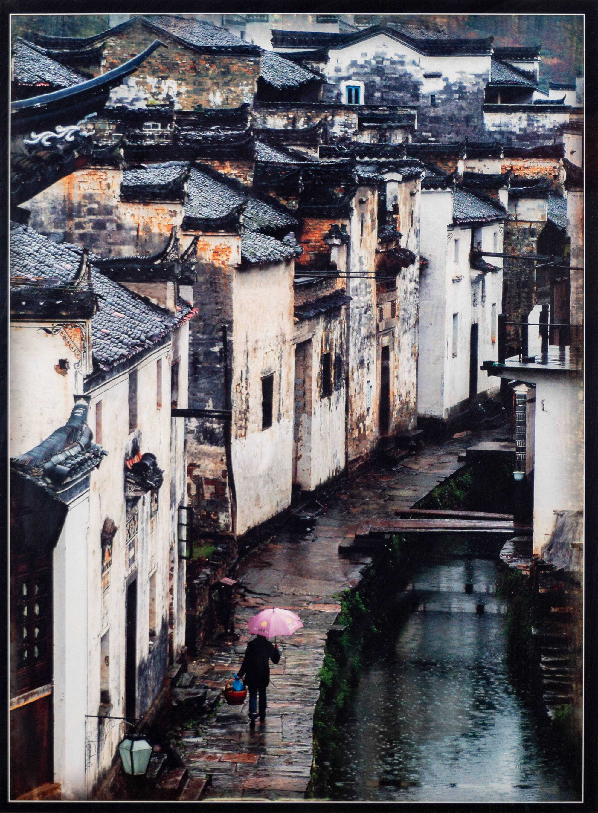 Chinese city scene along canal, rainy day.  Woman in lower left with basket and pink umbrella.